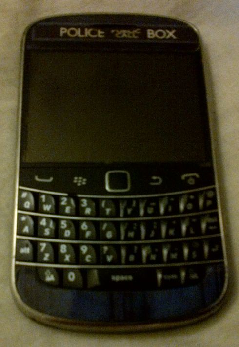 A BlackBerry Bold 9900 with a sticker on it that makes it look like the TARDIS from Doctor Who - a blue police box
