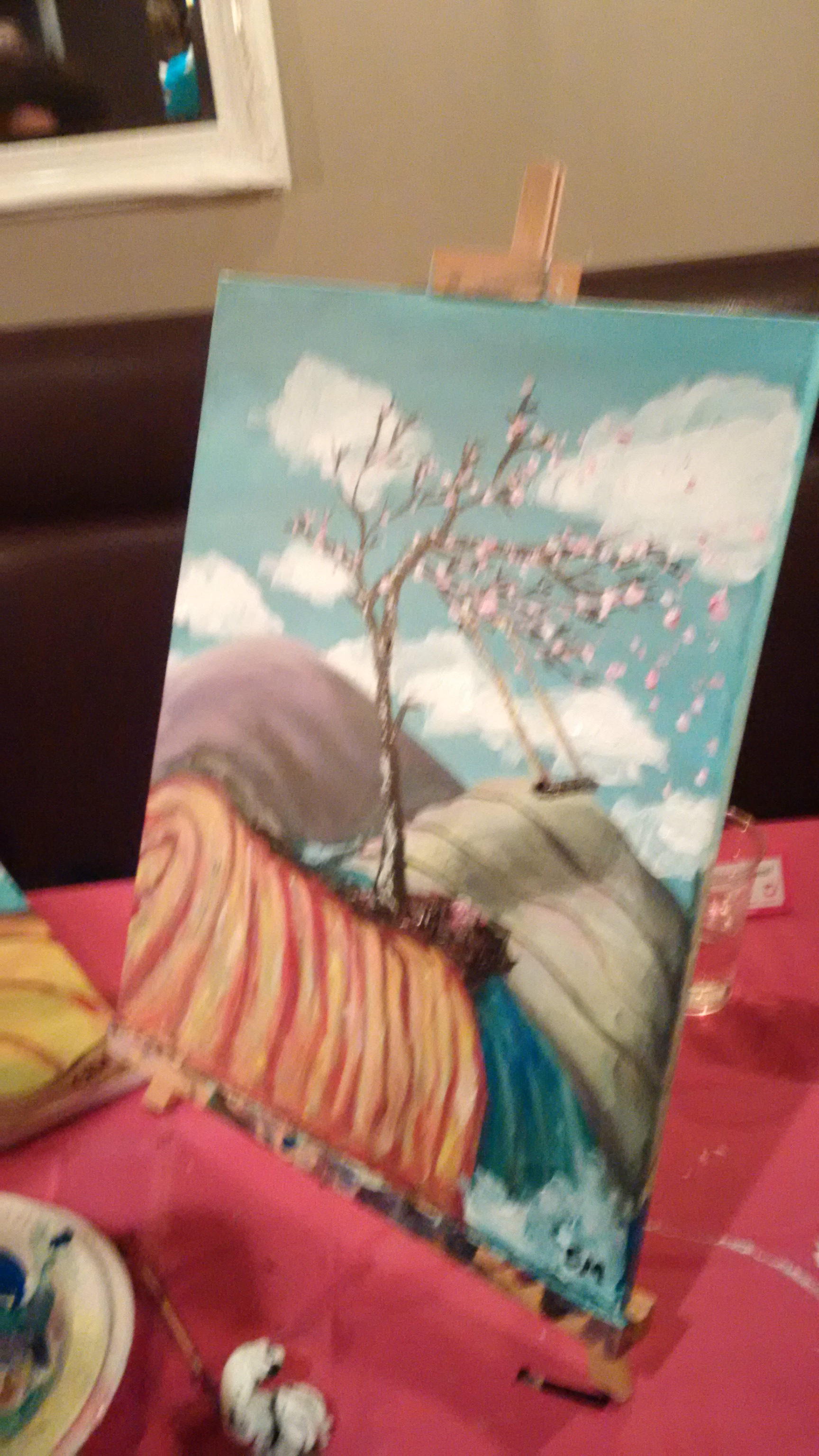 A tree without leaves in a field but with flowers on the tree instead of bare branches and a swing dangling from a branch
