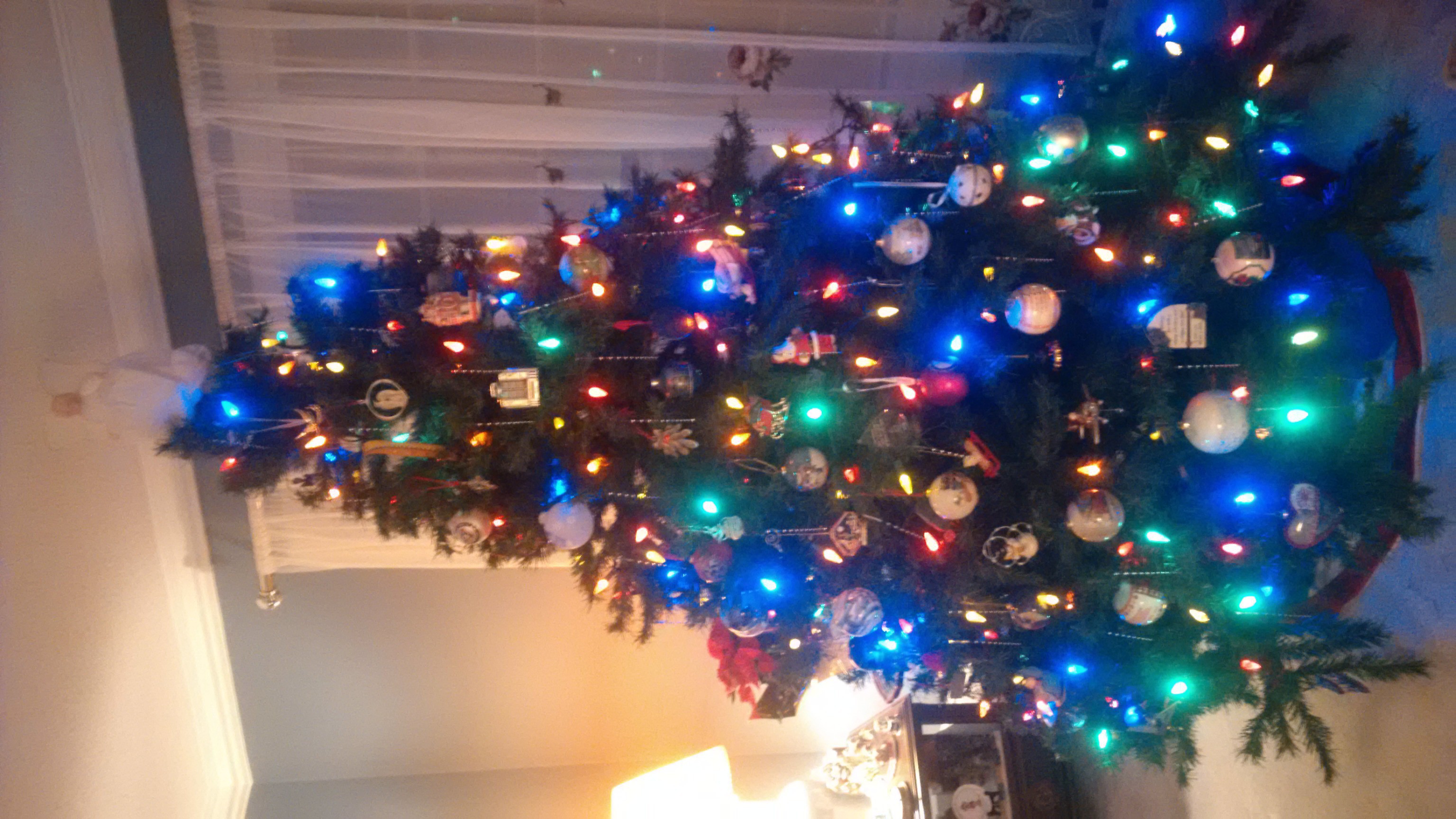 A decorated Christmas tree with multi coloured lights and an angel on top 