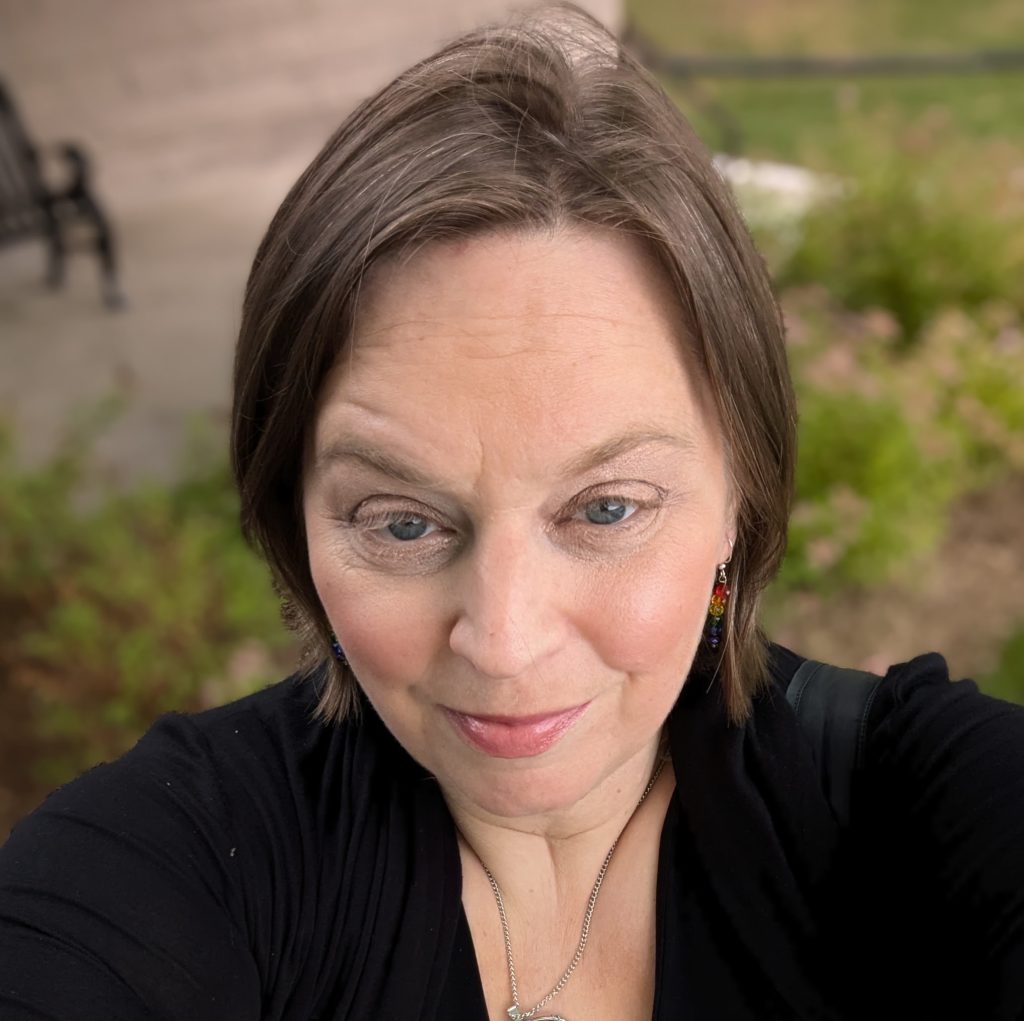 A woman with short light brown hair and blue eyes smiles for the camera.